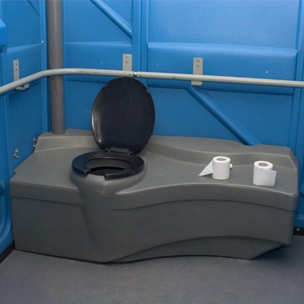Interior of an ADA accessible portable toilet with raised seat and grab bar