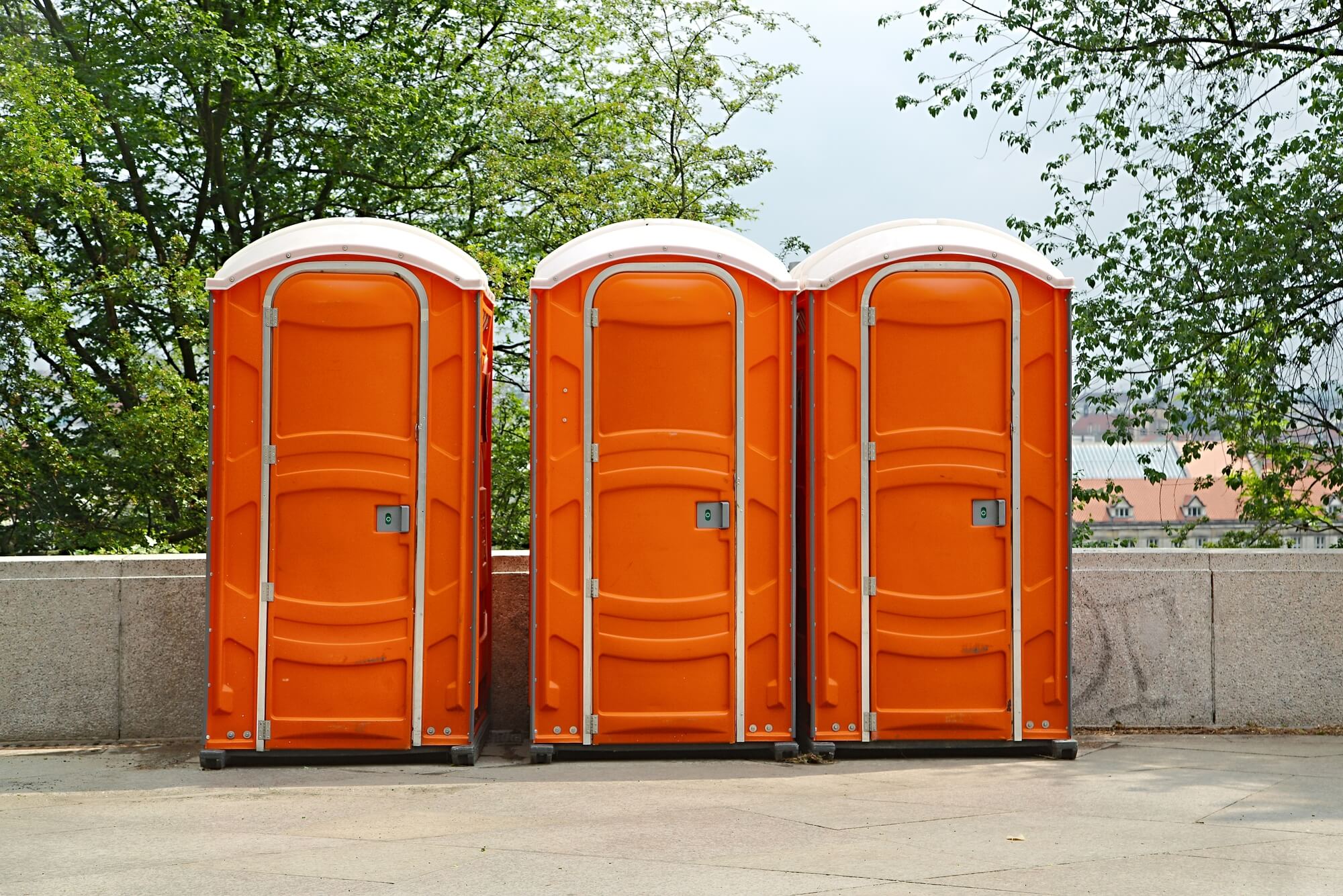 Row of heavy-duty orange portable toilets on an industrial site