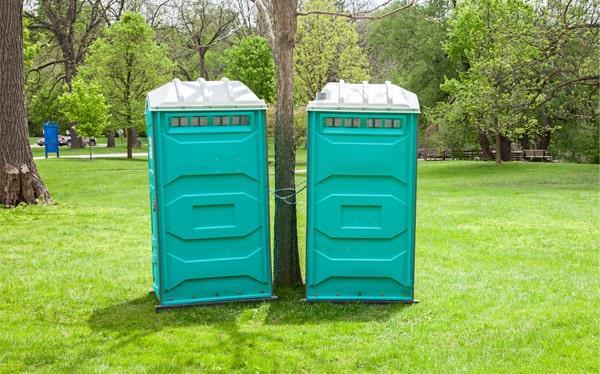Pair of teal portable toilets set up in a park for a short-term rental